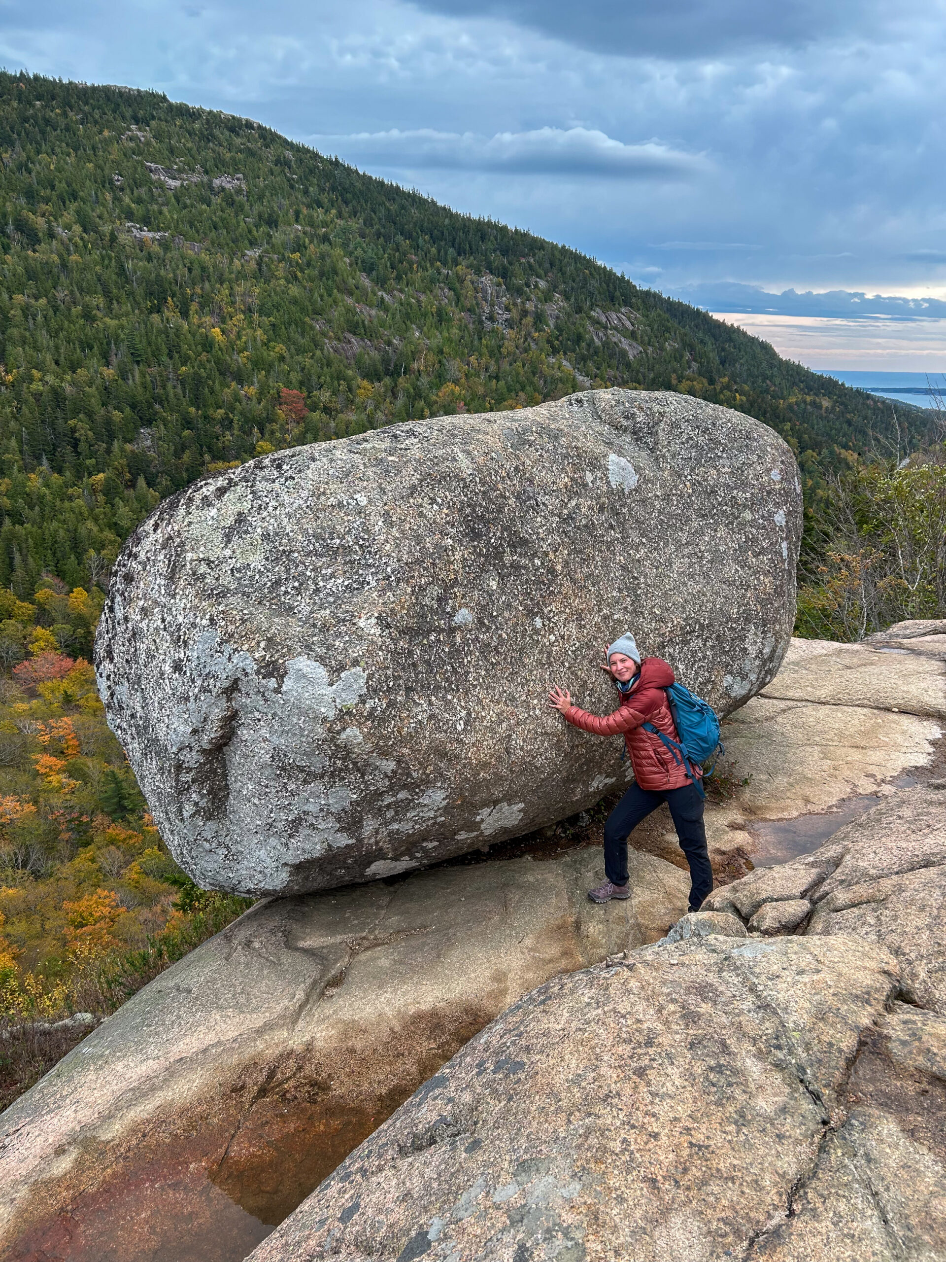 Person standing beside Bubble Rock on South Bubble in Acadia National Park